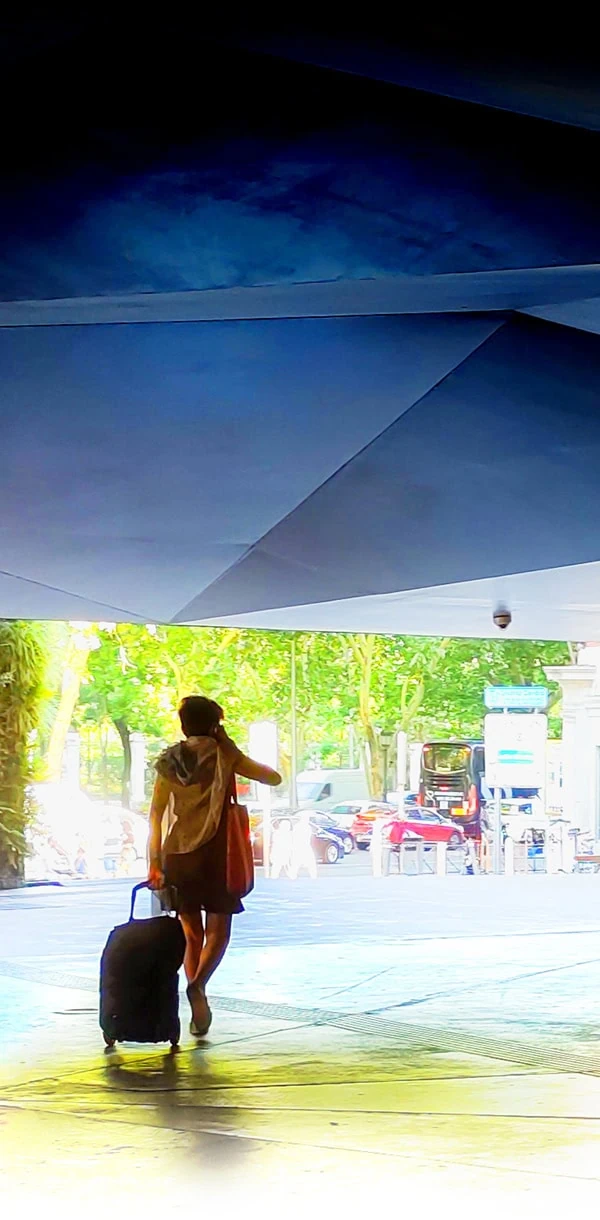 Mujer con maleta bajo la marquesina geométrica del CaixaForum Madrid