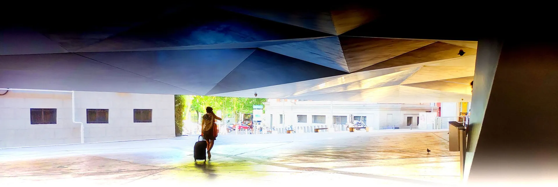 Mujer con maleta bajo la marquesina geométrica del CaixaForum Madrid